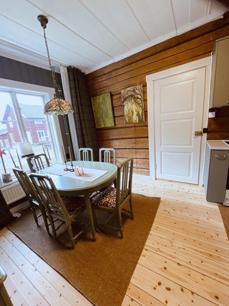 Matbord vid fönstret mot en timrad vägg